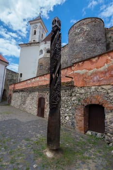 An ancient blackened by time wooden pillar covered with a fringe of bizarre patterns. Standing in the courtyard of an ancient fortress.