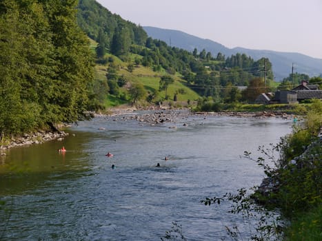 people bathing in the river on the background of mountains