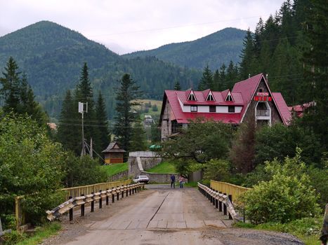 A small hotel building with a red roof and a road leading to it