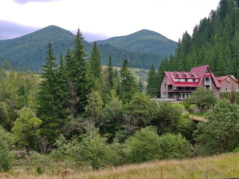 tiled roof of a residential complex lurking in green undergrowth at the foot of the mountain