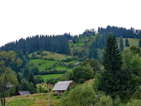 Small rural houses located in a chaotic order along the hillside among green trees and bushes.