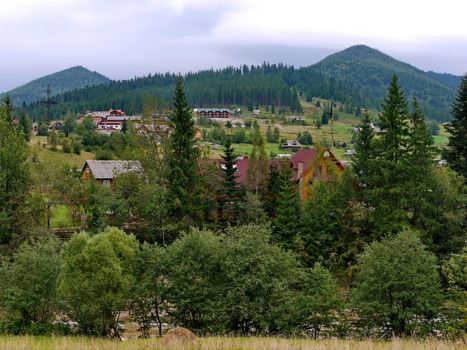 A panorama of wooded mountains near the village with hotels located near the mountain river