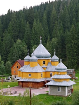 neat and well-groomed church with domes on the background of a dense green forest