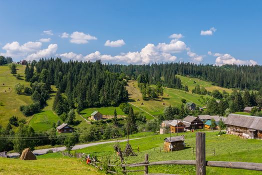 Beautiful countryside with neat rural houses standing on different sides of the road and farms with already cleaned and still lying dry hay.