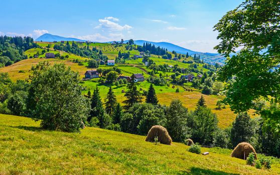 A small rural village with beautiful houses at the foot of the gentle green mountains