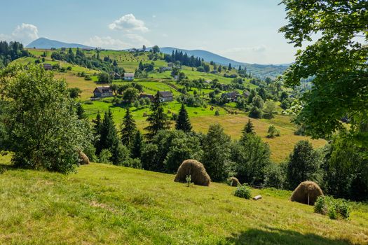 A picturesque view of a rural village located in the middle of green mountain ranges