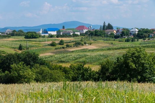 Multicolored roofs of small rural houses against the background of green misty mountains in the distance