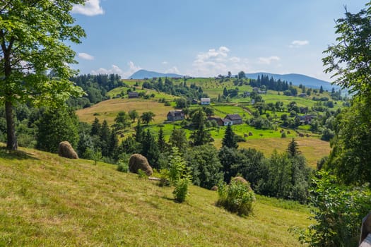 A sultry blue sky with rare clouds hung over a small village with beautiful mountain scenery around.
