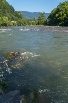 Stormy rapid flow of the river against the backdrop of a small church and endless mountains