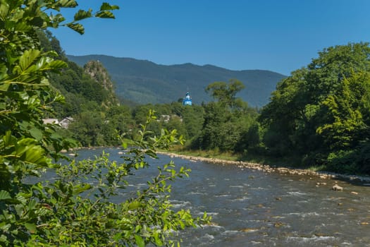 A fast mountain river against the background of a church temple among green lush trees