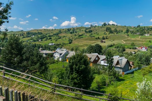 the street of the Carpathian village on the valley with a dense number of buildings