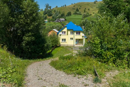 The road in the countryside is strewn with gravel leading down to the house in two floors with a tiled roof and two satellite dishes.