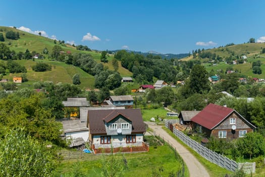 The panorama was between hills with green streets and rare buildings on the background of the distant mountains