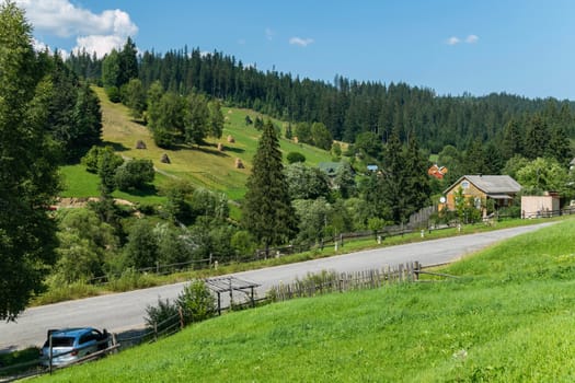A country road on the slope of a green mountain and small houses