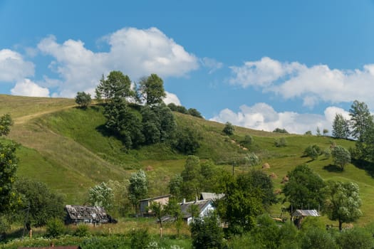 Small old rural houses near the slope of a green steep mountain
