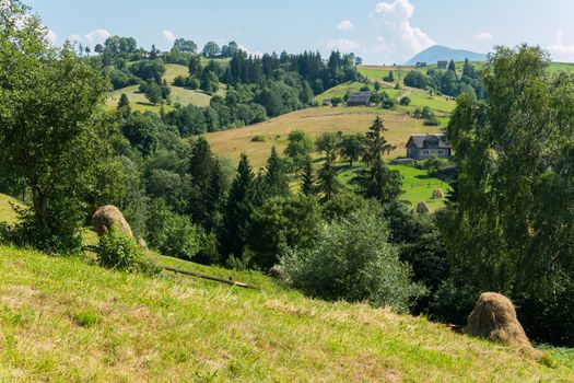 A place with hills and plains. Between these haystacks and houses