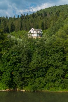 three-storey house in the forest more often with a mountain river in the foreground