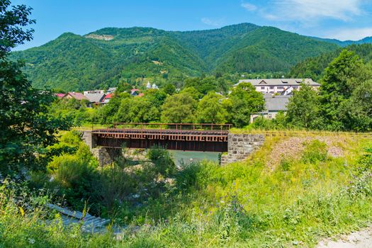 railway bridge on the background of roofs of houses and picturesque green mountains in the distance