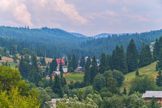 greens of forests and mountains of blue sky with clouds and a small village in the valley