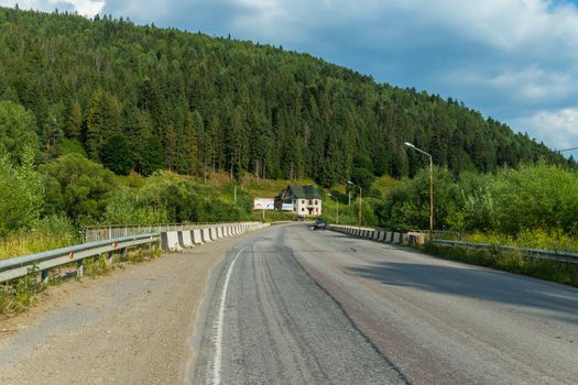 Asphalted road with a parapet on the road leads to a mountain where fires grow