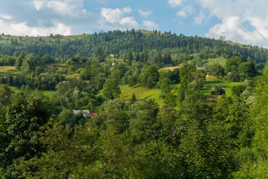 a panorama of green hills and somewhere the roofs of houses looking out among the greenery