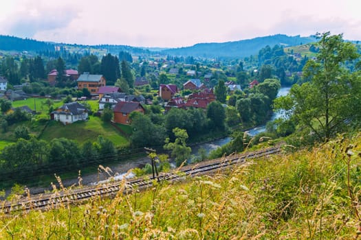 The mountain river is divided by railway from one side and village village on the other