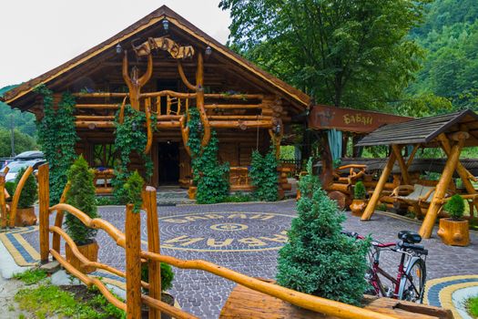 Authentic restaurant complex built of wood and paved with tiles on the background of green mountains. The best place to relax