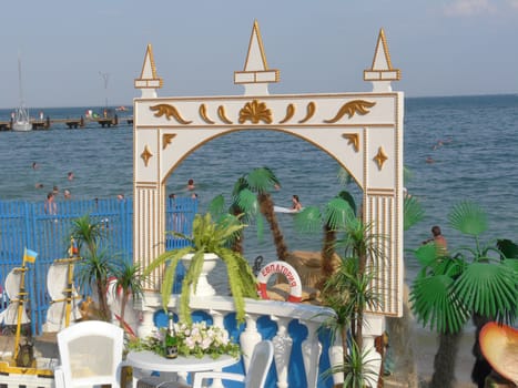 Summer terrace in Evpatoria, overlooking the blue, shining sea. In the water splashing holidaymakers with children