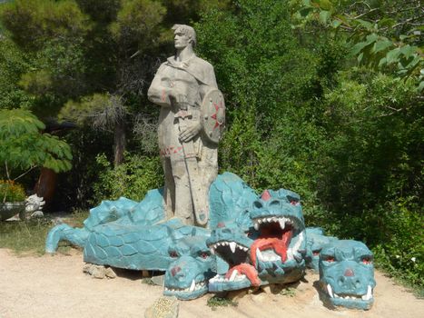 A concrete sculpture to a knight with a sword that defeated a three-headed dragon