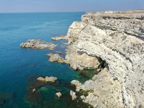 white rocky cliff in the blue sea, the ocean under the blue sky
