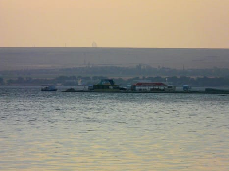 a river surface and a pier with summer cafes and a boat