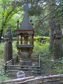 two statues of elders cut from a tree near the wooden carved tower with a squirrel from the fairy tale "About Tsar Saltan" among a thick deciduous forest. a fabulous resting place for the whole family