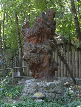 A wooden statue is called a fairy tale tree featuring various faces at an exhibition in the park