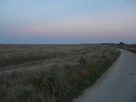 a deserted evening field with standing in the distance high-rise buildings