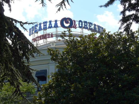 The facade of the Oreanda Hotel is seen between thick green bushes and lush trees of thick trees
