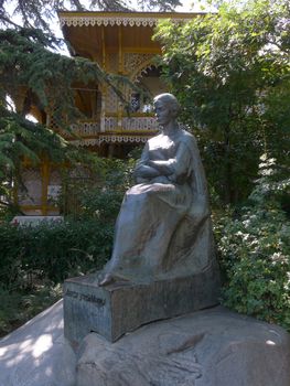 monument of a woman sitting with a pensive face carved out of a stone on the background of a gazebo in the park