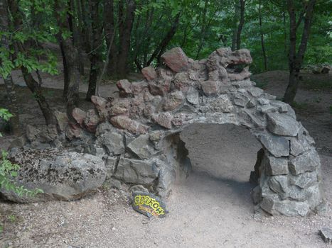 Sculpture in the park in the form of a dragon with a tail lined hand-made of stone and signed by a sign below.