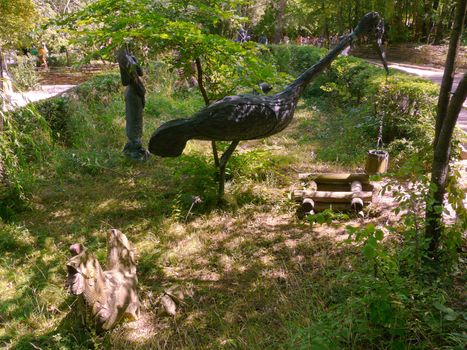 a statue of a wooden crane that takes a bucket of water from the well. Exhibition in the park