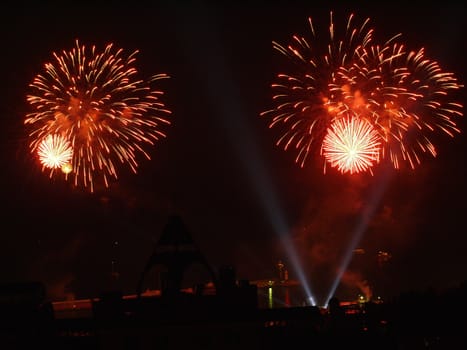 Bright bursts of fireworks in the night sky splashing rapturous spectators on their heads frantically enjoying such beauty.