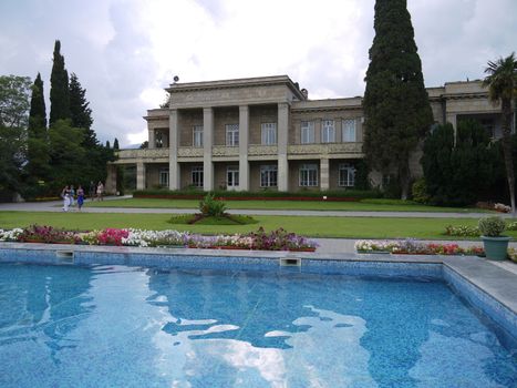 clear water pool in a park with a shaved lawn and flower beds in front of the house