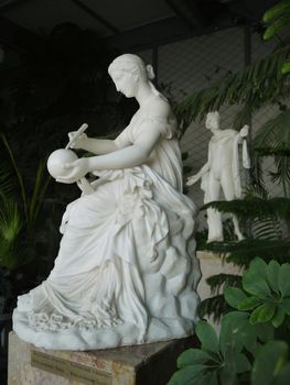 Statue of a woman drawing on a ball and statue of a man watching a woman