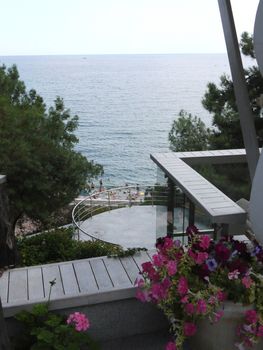 View from the balcony to the nearest beach with tourists on the background of the endless blue sea