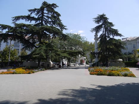 Park area with green trees and square flower beds on the sides