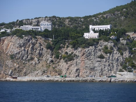 Rocky coastal zone with white houses, gray stones and green trees