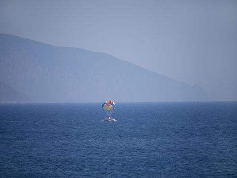 Boat with vacationing tourists against the blue sea and the high rocky mountains in the distance