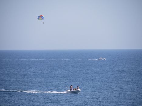 boat with a man on a parachute and a motor boat in the middle of the sea