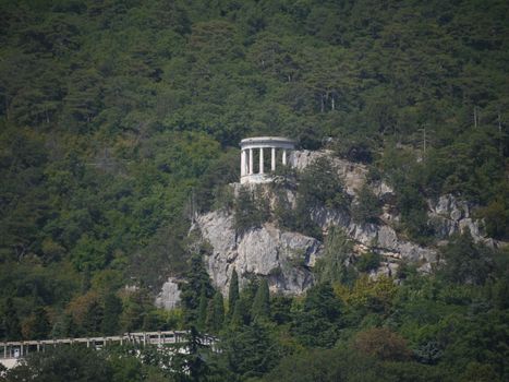 White arbor on a large rock, and around a green sea of trees
