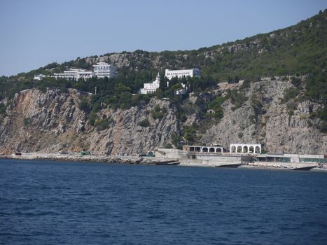 Stone coast of blue, deep sea with green trees and bushes