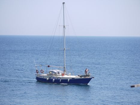 A small yacht with a plump man in a calm blue sea. Yana was named, probably in honor of his wife