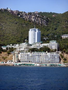 white hotels on the background of greenery on the beach with the beach in the resort town